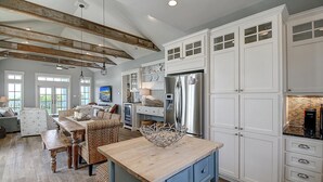 A spacious kitchen with white cabinetry, a central island, and a modern stainless steel refrigerator.