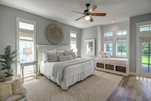 Une chambre avec un grand lit, un ventilateur de plafond et une vue sur l’extérieur.