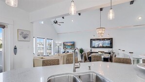 A modern kitchen with a large island, double sinks, and pendant lighting. - Beyond Paradise 119 SE (Port Aransas)