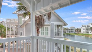 A coastal house with a balcony overlooking a body of water, surrounded by similar houses. - Beyond Paradise 119 SE (Port Aransas)