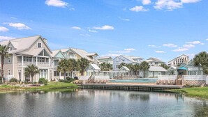 A waterfront property with multiple houses, a swimming pool, and a calm lake. - Beyond Paradise 119 SE (Port Aransas)