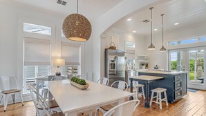 Une cuisine moderne avec des meubles blancs, un îlot central et des luminaires suspendus.