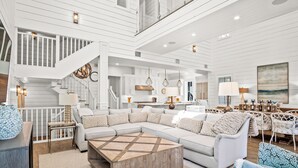 A spacious living area with a large L-shaped sectional sofa, a wooden coffee table, and a staircase leading to an upper level. - Golden Daze 239 SE (Port Aransas)