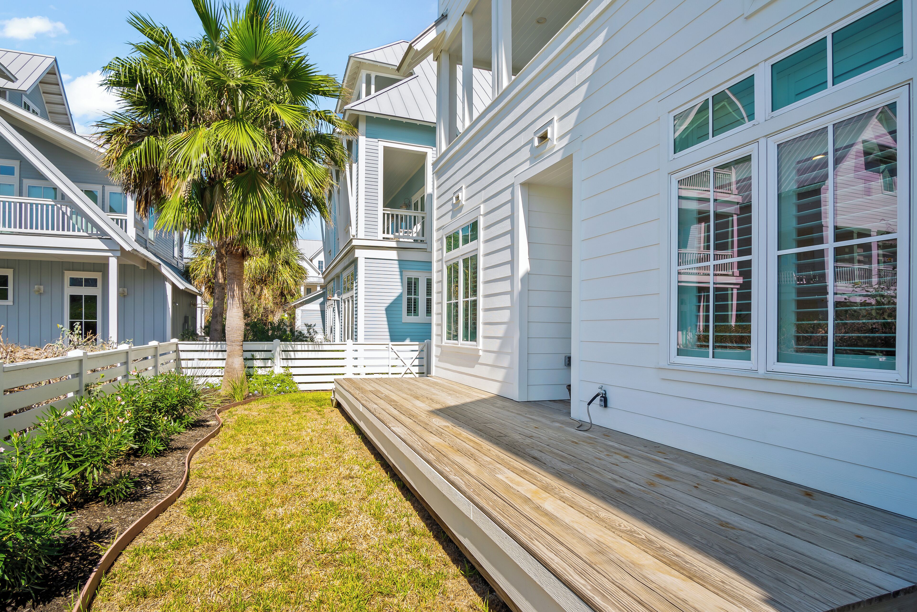 A coastal house with a wooden deck, white siding, and a white fence.