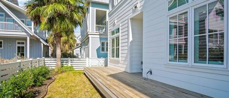 A coastal house with a wooden deck, white siding, and a white fence.