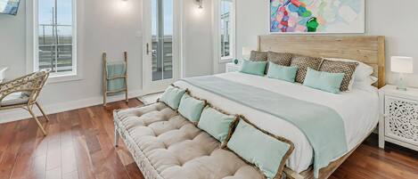 A spacious bedroom with a large bed, a wooden headboard, and a colorful abstract painting above it.