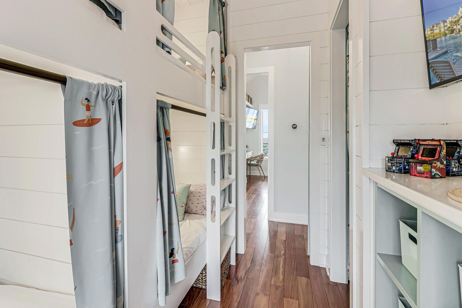A hallway with bunk beds, a TV, and arcade games.