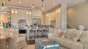 A spacious living room with a sofa, a coffee table, and a dining area with chairs and a table. - Island Time TC 4102 (Port Aransas)