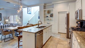 Una cucina moderna con isola centrale, elettrodomestici integrati e zona pranzo con divano e sedie.