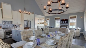 A spacious kitchen with modern appliances, a dining area with a large island, and a cozy seating area with wicker furniture. - Coastal Charm 258 HI (Port Aransas)