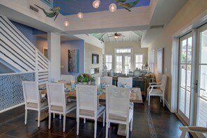 Enjoy a spacious interior with a high ceiling, fan, and dining area featuring wicker chairs and a table.