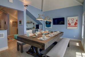 Enjoy meals in this dining area with a long table, modern kitchen, and comfortable dining bench.