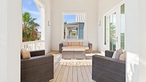 A covered outdoor seating area with wicker furniture and a central sofa. - High Tide 243 HI (Port Aransas)