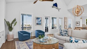 A spacious living room with a large window, a ceiling fan, and a dining area with wooden furniture. - High Tide 243 HI (Port Aransas)