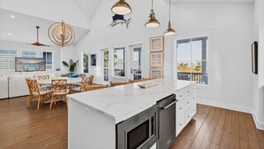 A spacious kitchen with a large island, white cabinetry, and pendant lighting. - High Tide 243 HI (Port Aransas)