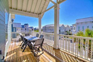 A wooden deck with a table and chairs, overlooking a row of houses. - Hip Nautic 113 WI (Port Aransas)