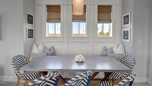 A dining area with a large table, six chairs, and a hanging light fixture. - Hip Nautic 113 WI (Port Aransas)