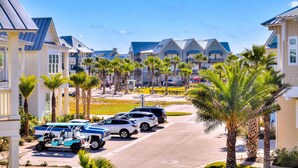 A coastal residential area with multiple-story houses, a paved road, parked vehicles, and palm trees. - Hip Nautic 113 WI (Port Aransas)
