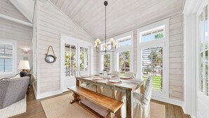 A dining area with a wooden table, bench, and chandelier. - A Shore Thing 188 RO (Port Aransas)