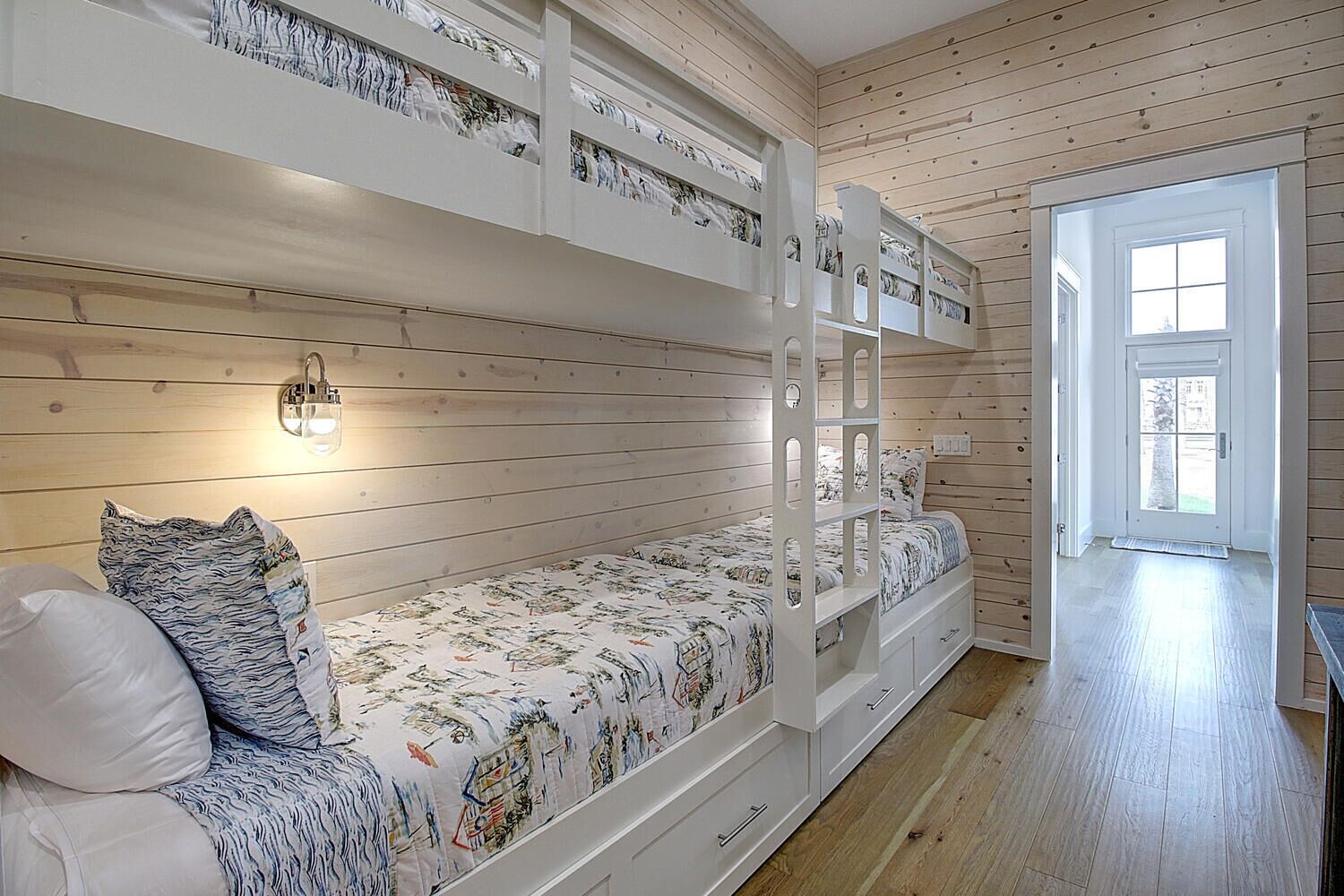 Dormitorio con literas, cabecera blanca, mesita de noche y velador.
