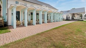 A building with a covered patio area featuring light blue columns and wicker furniture. - Island Breeze TC 1104 (Port Aransas)