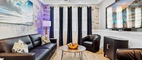 A modern living room with a sofa set, a coffee table, a TV, and a ceiling fan.