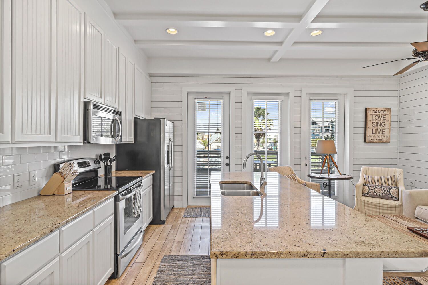 A modern kitchen with white cabinetry, stainless steel appliances, and a granite countertop.