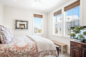 Relax in this serene bedroom with a large bed, wooden bench, and TV mounted on a cabinet, offering a view of the surrounding area.