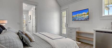 Un dormitorio con cama, escritorio, televisor y vista a una piscina.