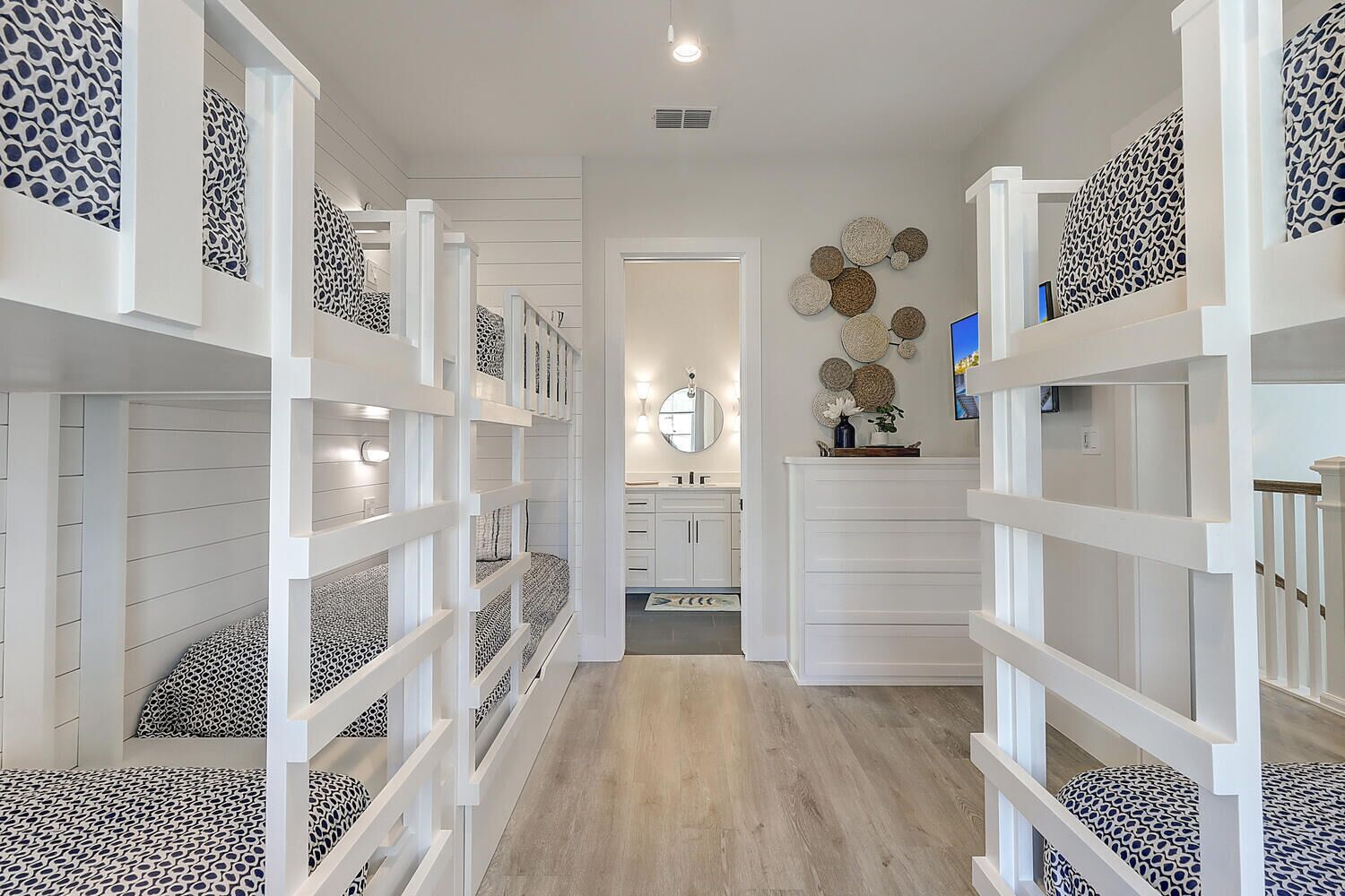 A hallway with bunk beds, a mirror, and a decorative wall.