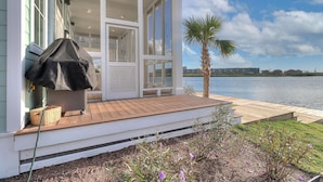 A waterfront property with a covered porch, a palm tree, and a view of the water. - Keepin' It Reel 234 LAK (Port Aransas)
