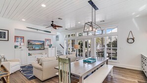 A spacious living room with a wooden ceiling, a ceiling fan, and a large window with blinds. - Lollygag 107 ST (Port Aransas)