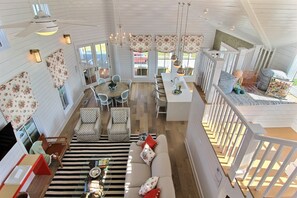 Relax in a spacious room with a central seating area, dining table, and kitchenette, offering views of the outdoors.