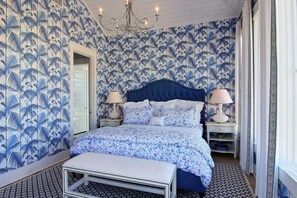 Coastal-inspired bedroom with a large bed, tufted headboard, and patterned rug.