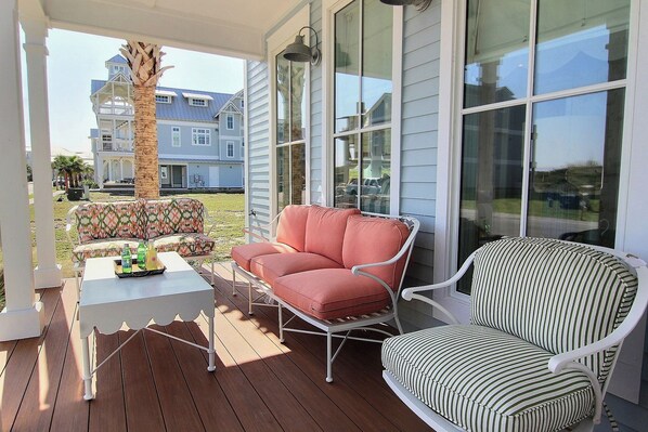 A covered outdoor seating area with two chairs and a table, overlooking a residential neighborhood. - After Dune Delight 247 SE (Port Aransas)