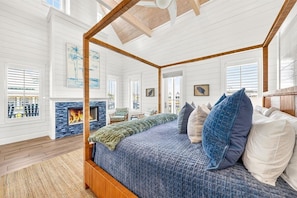Une chambre spacieuse dotée d’un lit à baldaquin, d’une cheminée et de grandes fenêtres.