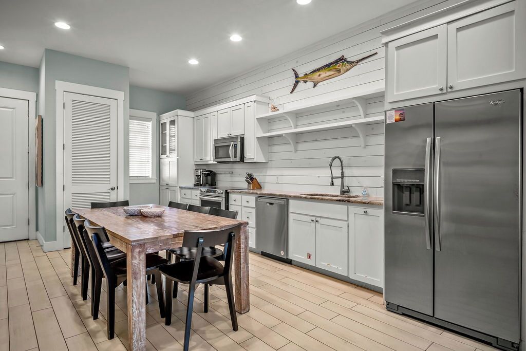 Una cocina moderna con armarios blancos, electrodomésticos de acero inoxidable y una mesa de comedor de madera.