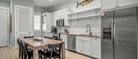 Una cocina moderna con armarios blancos, electrodomésticos de acero inoxidable y una mesa de comedor de madera.