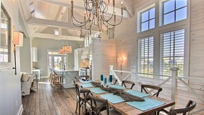 A spacious dining area with a wooden table, chairs, and a chandelier. - Oceanaire 196 RO (Port Aransas)