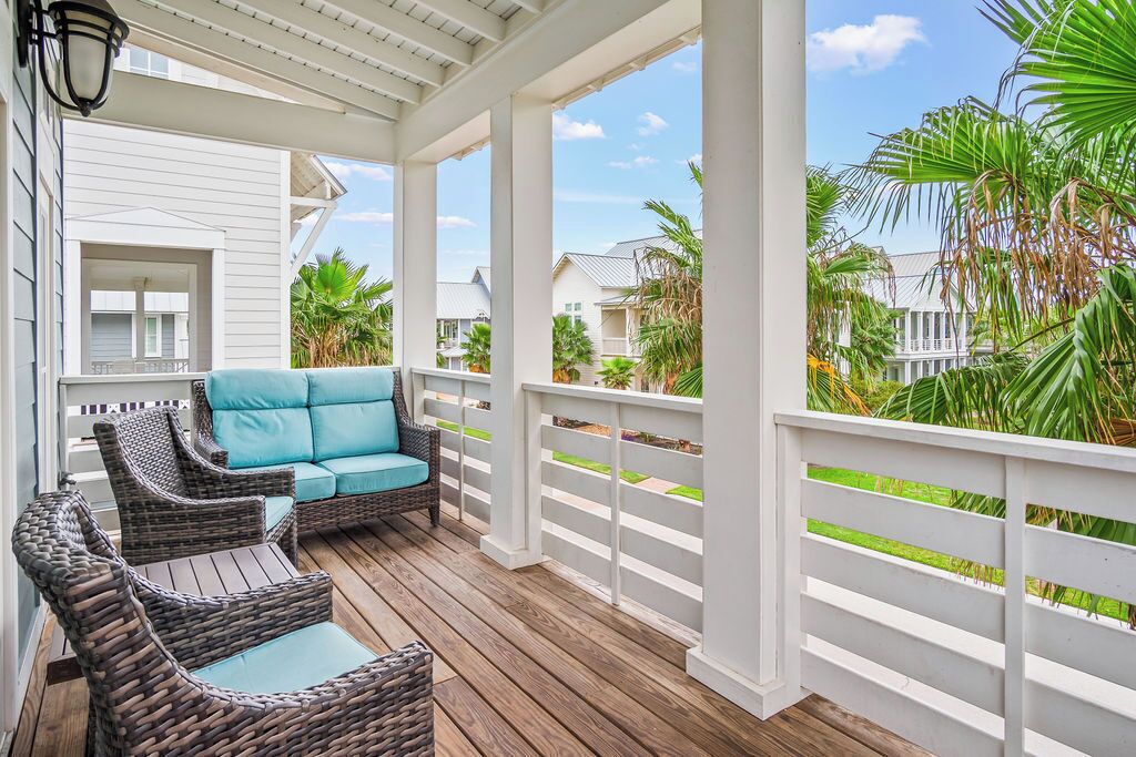 A covered outdoor area with wicker furniture and a view of neighboring houses.