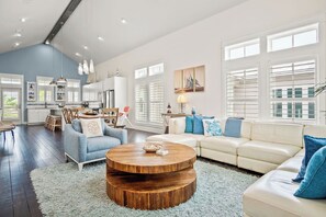 Relax in this airy living space with a light-colored sofa, white dining area, and modern kitchen.
