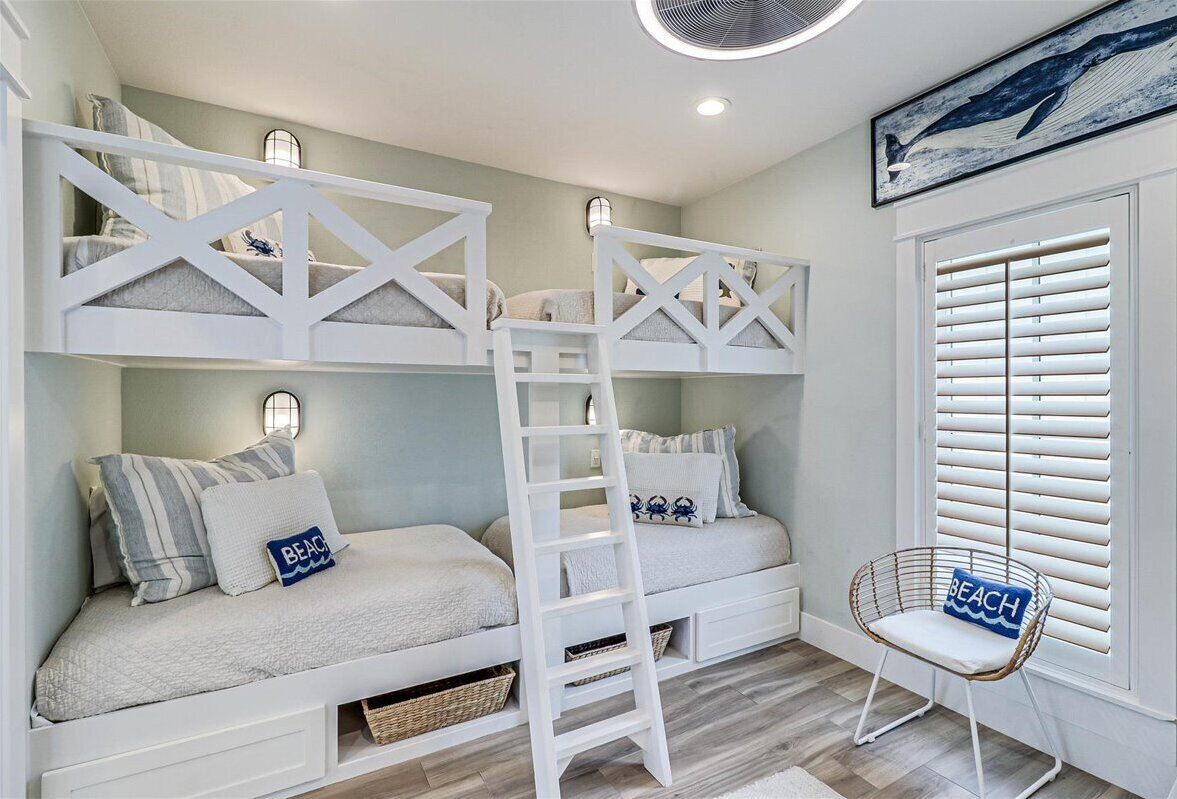 A bunk bed room with a ladder, a chair, and a window with blinds.