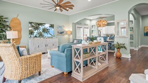 A spacious living room with a blue sofa, wicker chair, and a wooden coffee table. - Lovey Dovey 145 BE (Port Aransas)