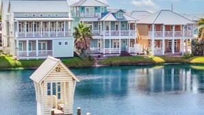 A waterfront property with multiple-story buildings, a dock, and a small wooden structure. - Lovey Dovey 145 BE (Port Aransas)