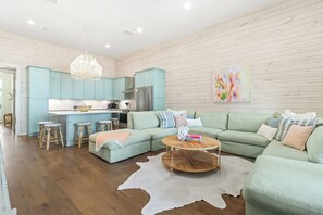 A modern living space with a kitchen, a large L-shaped sofa, and a dining area. - Southern Seaside TC 9103 (Port Aransas)