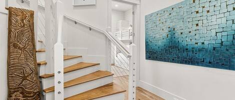 A staircase with wooden steps and white railings, leading to a room with a blue mosaic wall.