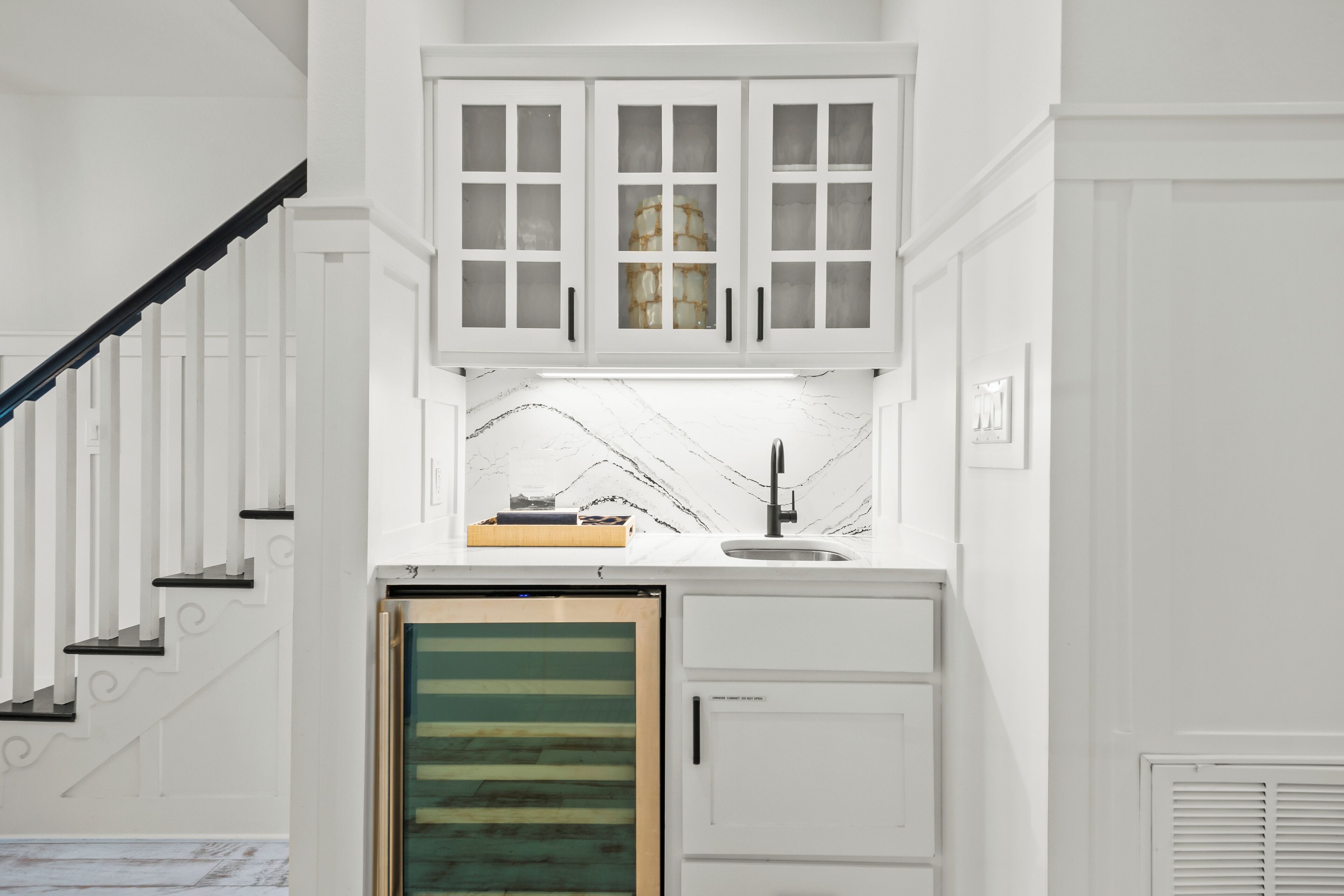 Una cucina con mobili bianchi, una parete di fondo in marmo e un forno integrato.