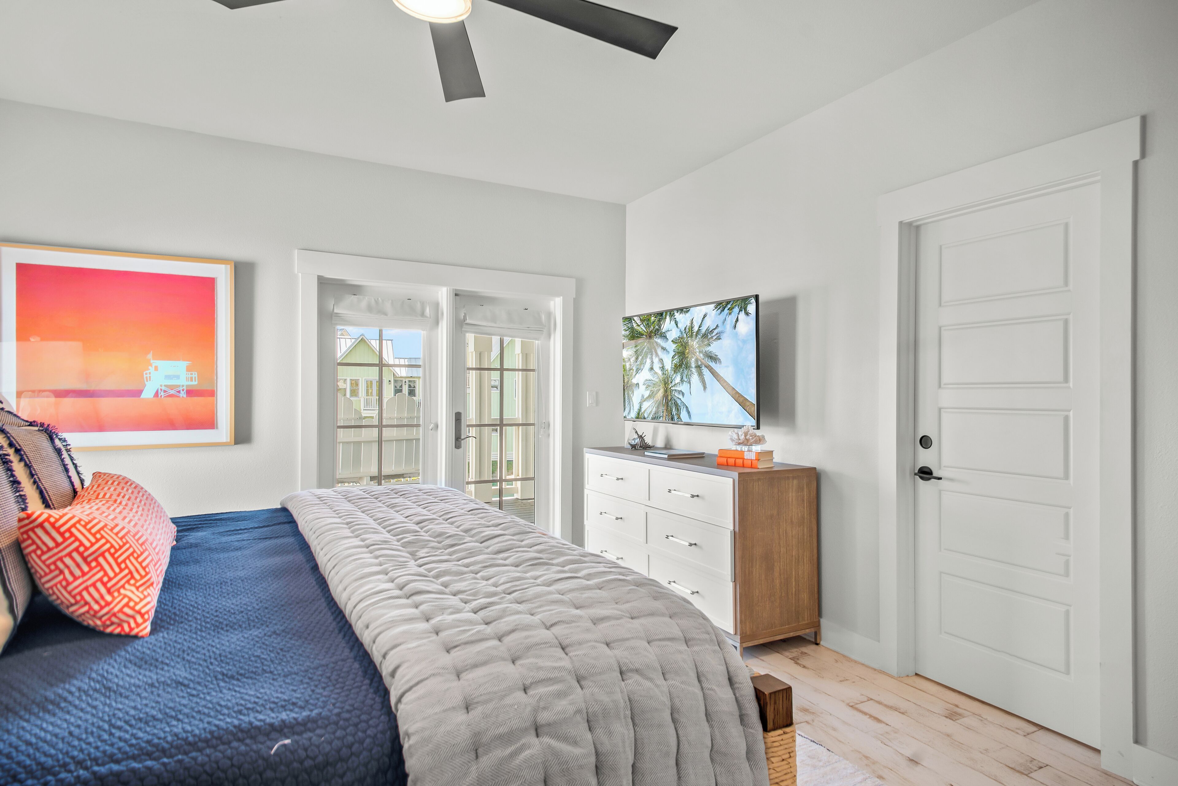 A bedroom with a bed, a dresser, a television, and a door.