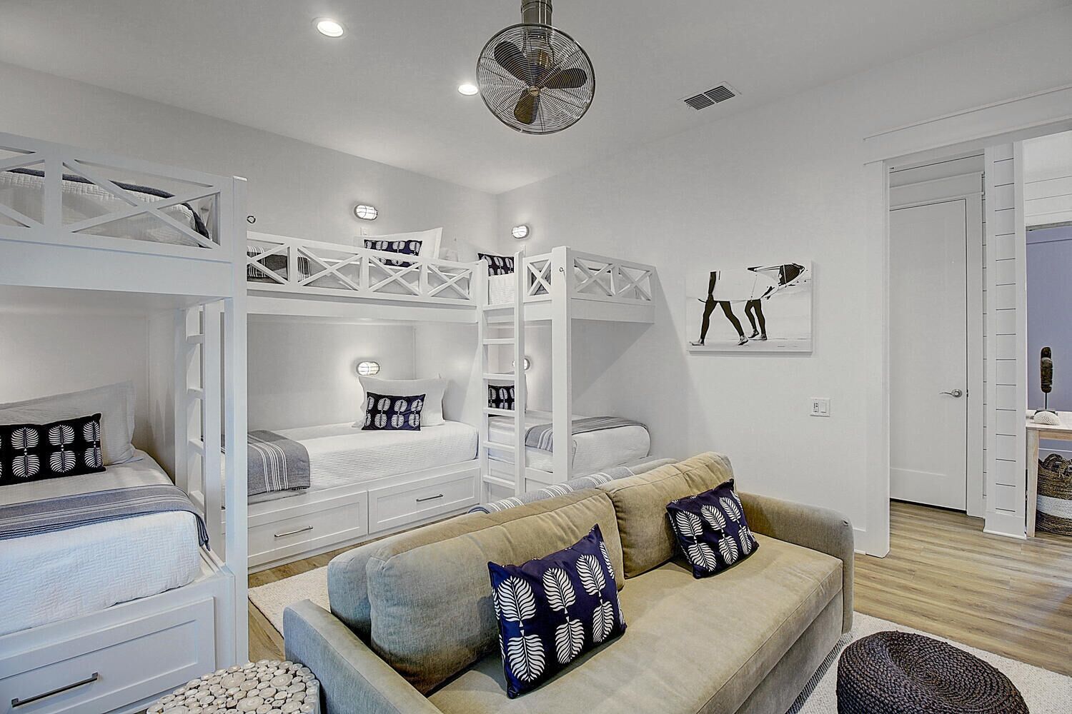 A modern bedroom with bunk beds, a sofa, and a fan.