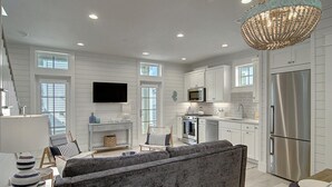 A modern kitchen with white cabinetry, stainless steel appliances, and a chandelier. - Seahorse Cottage 230 RO C1 (Port Aransas)